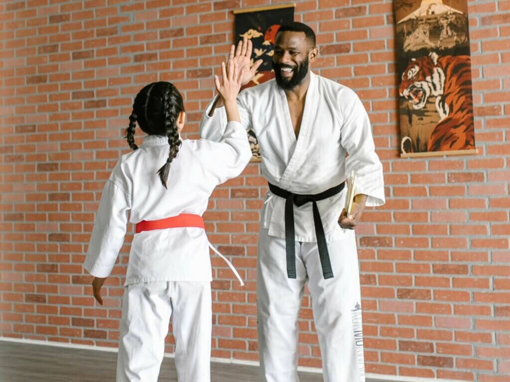 Ein Mann und ein Mädchen im Karate-Anzug klatschen sich ab